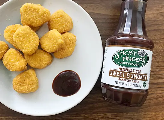 sticky fingers bbq sauce bottle with chicken nuggets next to it