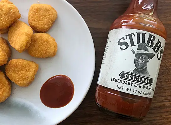 a bottle of stubbs bbq sauce with chicken nuggets next to it