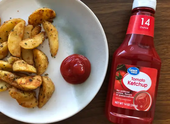 great value ketchup bottle next to fries and ketchup on plate.