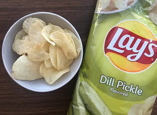 a bag of lays dill pickle next to a bowl of chips