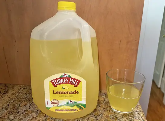 A jug of Turkey Hill brand lemonade next to a small glass of the beverage.