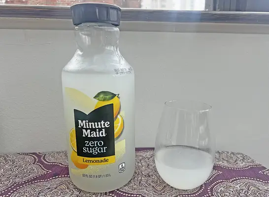 A bottle of Minute Maid Zero Sugar lemonade next to a small glass of the beverage