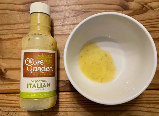 olive garden dressing in a bottle with bowl beside it.