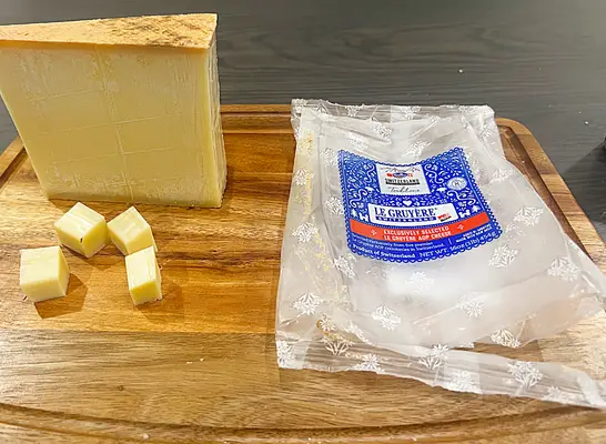 a block of le gruyere cheese on a cutting board