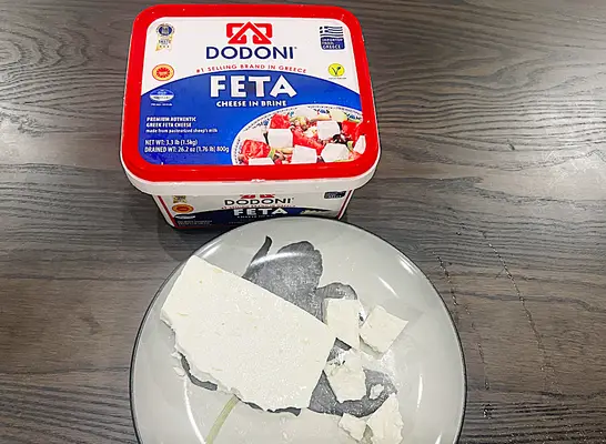 a container of dodoni feta cheese with some on a plate