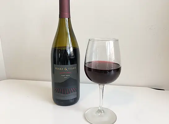 a bottle of pinot noir next to a glass of wine