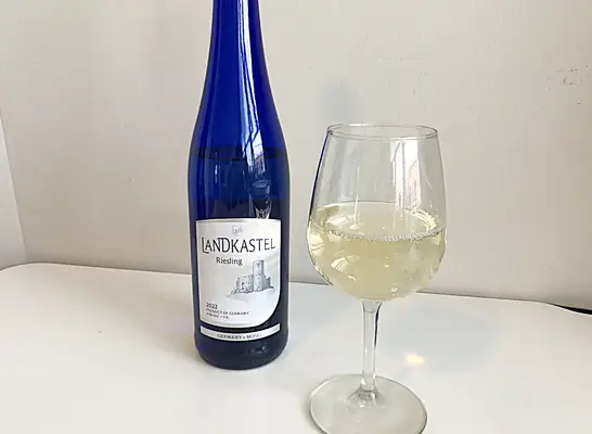 a bottle of riesling next to a glass of white wine