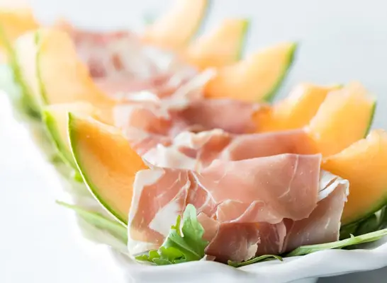 Canteloupe wrapped in prosciutto served on a plate