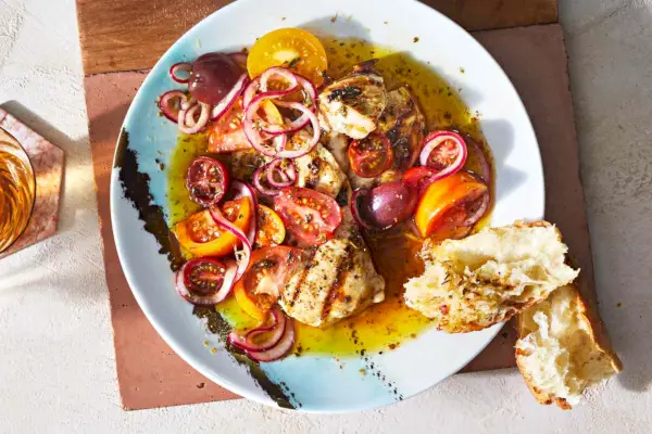 Einzelner Teller mit gegrilltem Hähnchen mit marinierten Tomaten und Zwiebeln