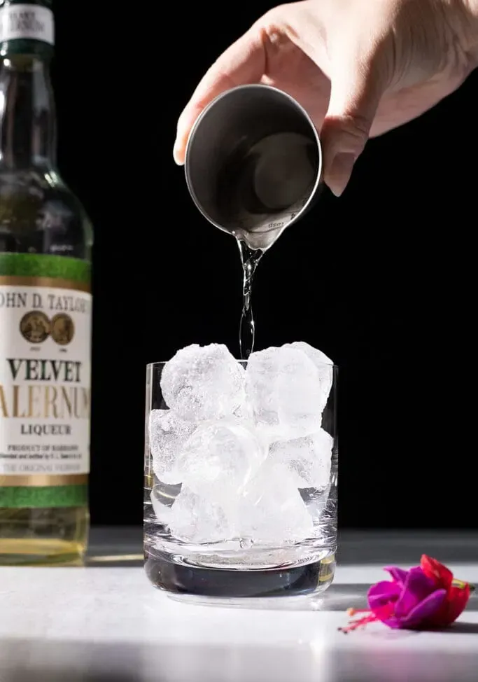versando il Falernum sul ghiaccio.' loading='lazy' title=