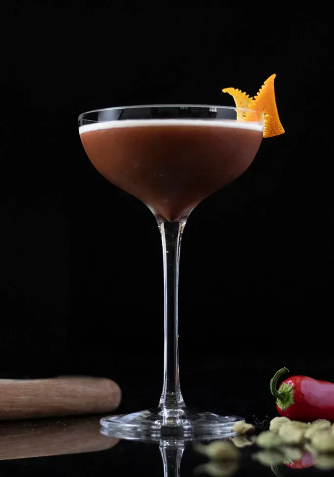 una copa de cóctel llena de un martini espresso y adornada con una piel de naranja' title=