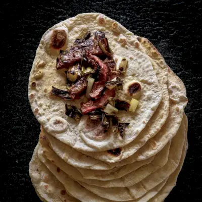 Tortilhas de massa fermentada com bife carbonizado e molho de cebolinha