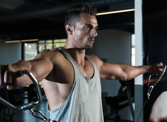 muscular man doing cable machine lateral raise exercise