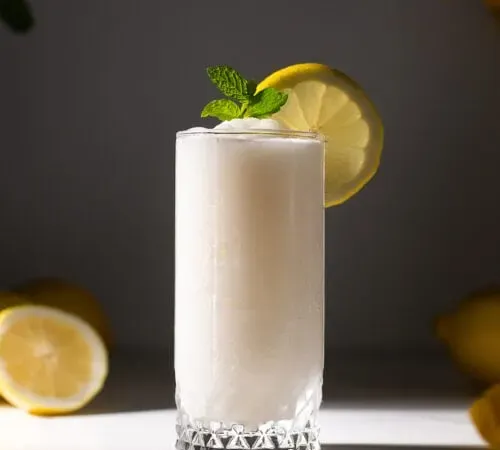 um copo alto cheio de limonada branca congelada.' title=
