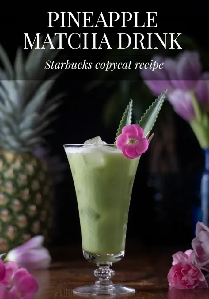 Ein Glas hausgemachtes Ananas-Matcha-Getränk, garniert mit Ananasblättern und einer rosa Blume' title=