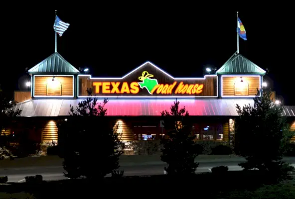 Das Restaurant Texas Roadhouse erleuchtet den Abendhimmel mit seiner markanten Leuchtreklame in Parker, Colorado.