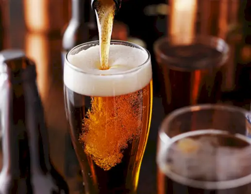 Ein Bier aus einer Flasche in ein Glas gießen