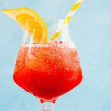 Spritz Campari ve skle s plátkem citronu a slámou.