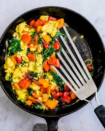 Petit-déjeuner sain brouillé avec des légumes dans une poêle.