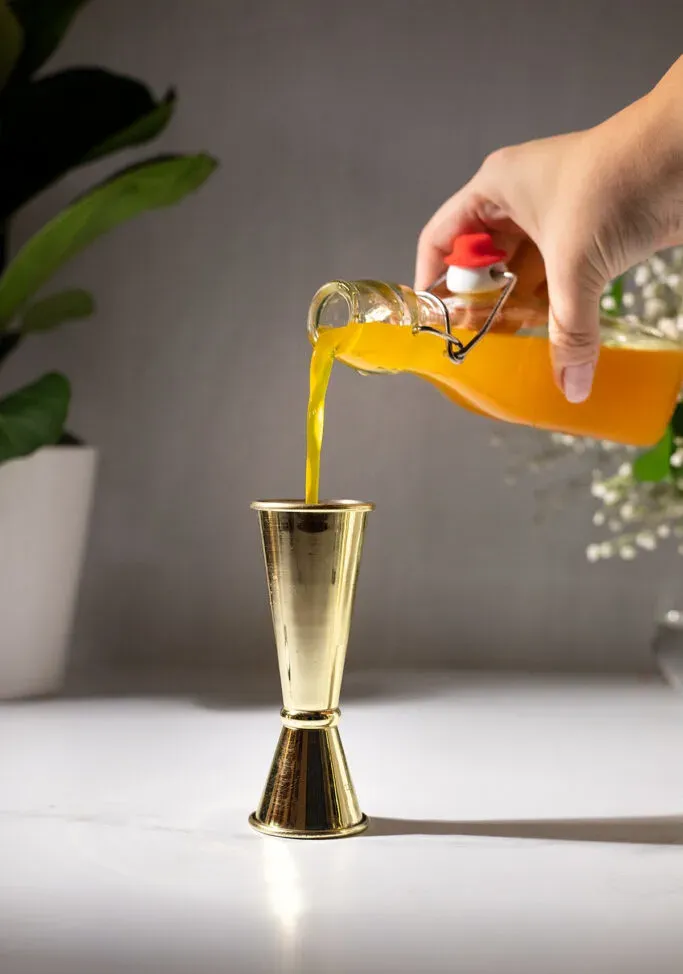 versando lo sciroppo di curcuma in un jigger per lingotti d'oro.' title=