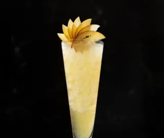 リンゴの扇子が添えられた背の高い黄色い飲み物。' title=