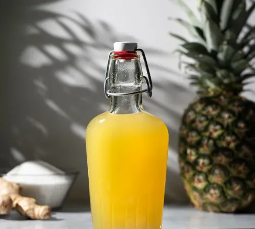 Bügelverschlussflasche mit gelbem Ananas-Ingwer-Sirup.' title=