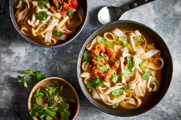 카오 소이(Khao Soi)는 고수와 민트 잎으로 장식된 검은색 그릇에 담겨 제공됩니다.