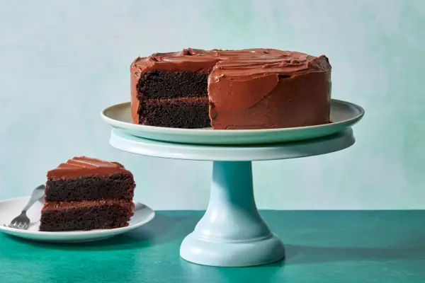Un support à gâteau avec un gâteau double au chocolat à deux étages avec une tranche retirée