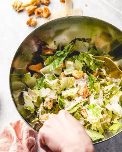 Misture a salada César em uma tigela.
