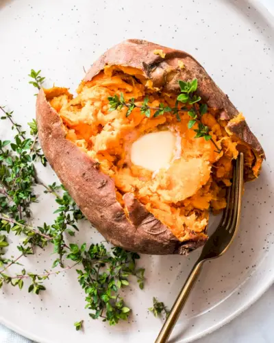 Batata doce no microondas com manteiga no prato.