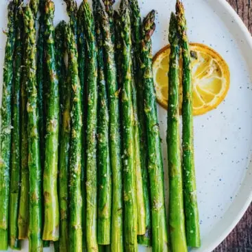 Receita de espargos grelhados com lanças no prato com rodela de limão.