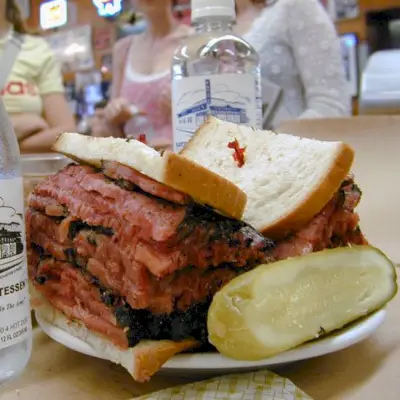 Ein riesiges Pastrami-Sandwich, serviert mit einer großen Gurke bei Katz