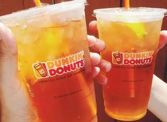 two hands holding two cups of Dunkin