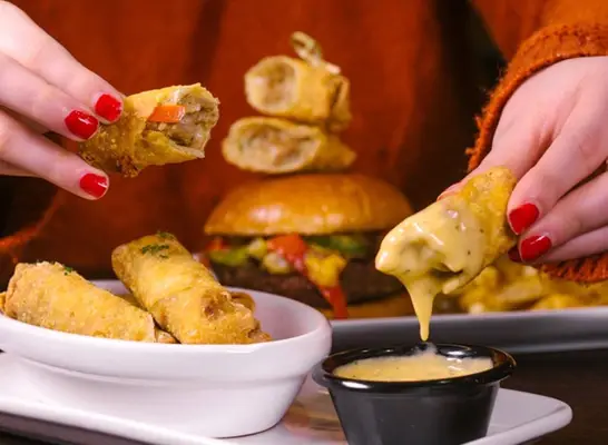 a plate of leeann chin egg rolls and sauces arranged on a plate against a bright designed yellow background