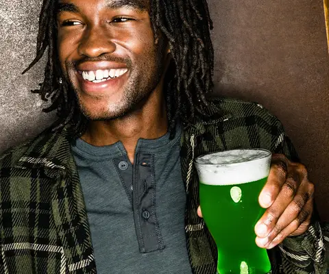 Happy customer drinking green-colored beer on St. Patrick