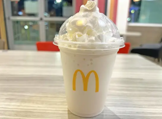 A vanilla milkshake in a see-through plastic cup from McDonald