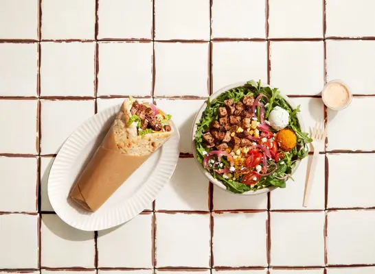 Cava Steak Mezze Salad and Steak + Feta Pita on tile background