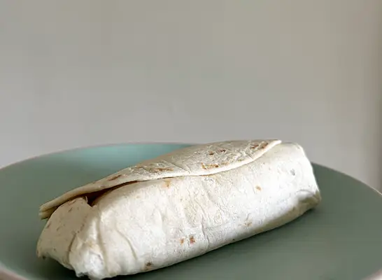 a mcdonalds breakfast burrito on a green plate.