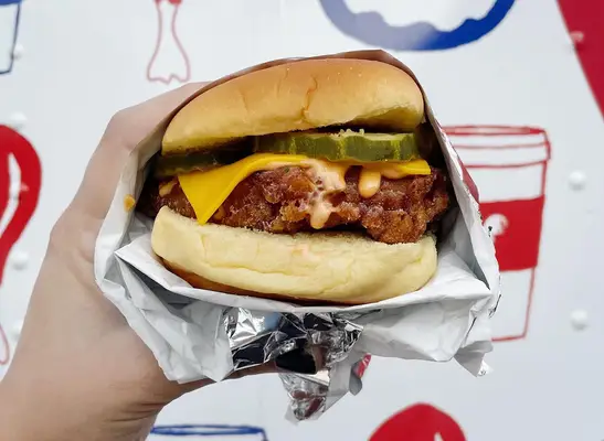 A fried chicken sandwich with cheese, pickles, and Rooster sauce from Philadelphia