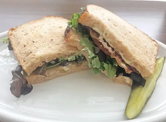 a panera blt cut open on a white plate.