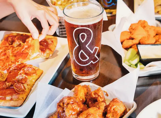 A pint of beer surrounded by plates of food at Dave & Buster