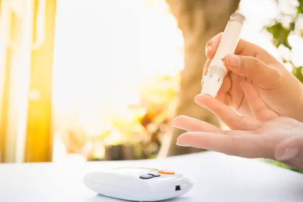 female using lancelet on finger to checking blood sugar level by Glucose meter