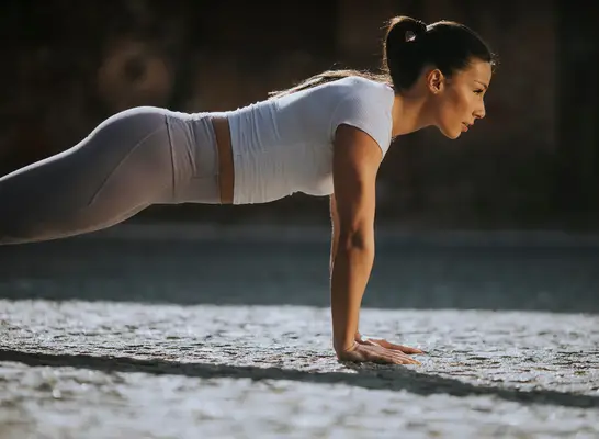 woman doing pushups, concept of a no-gym workout to melt belly fat