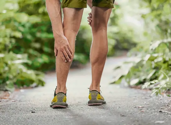 close-up man touching his sore leg while out on a walk