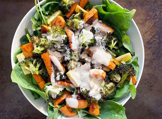 whole 30 roasted vegetable salad with tahini dressing in white bowl