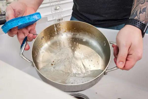 Osoba myjąca Tramontina Tri-Ply Plated 10-częściowy zestaw garnków ze stali nierdzewnej