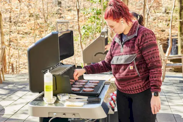 Mulheres grelhando hambúrgueres na churrasqueira a gás de 3 queimadores Weber Genesis E-325s