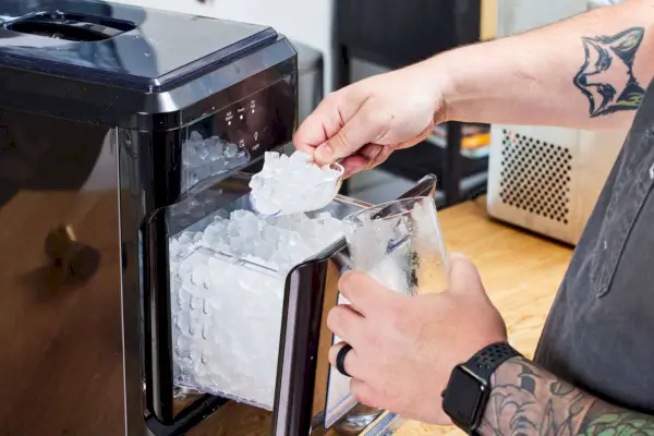 Una persona retira hielo de la máquina de hielo en pepitas masticables crujientes para encimera EFIC255 de FRIGIDAIRE Gallery
