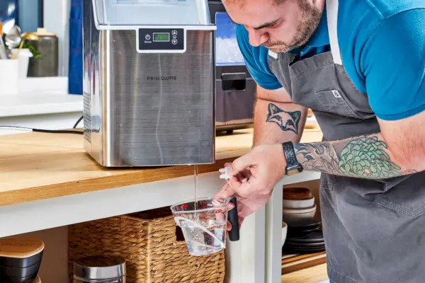 Una persona drena agua de la máquina de hielo Frigidaire Countertop Nugget Ice Maker V2