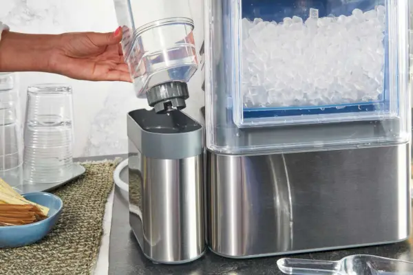 Persona que llena el agua en la máquina de hielo en pepitas Ge Profile Opal 2.0